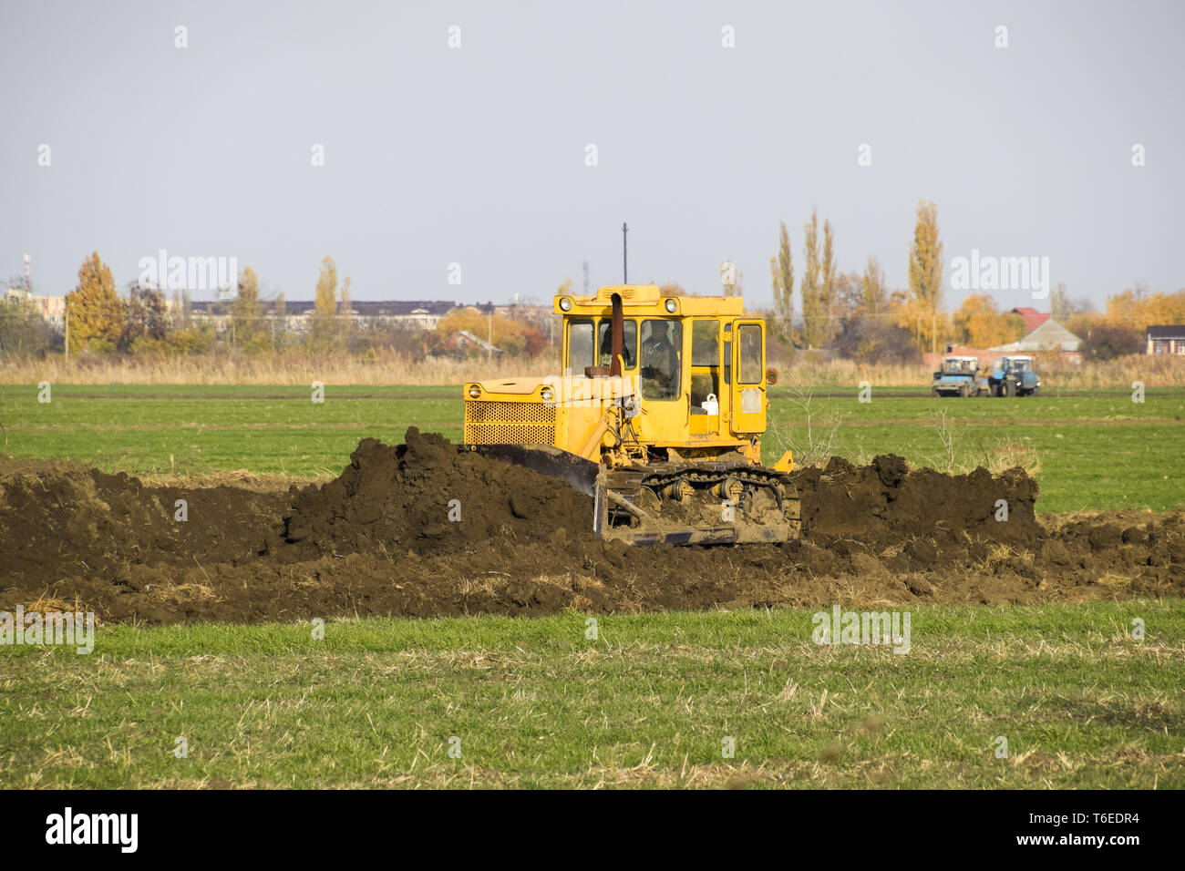 The yellow tractor with attached grederom makes ground leveling Stock