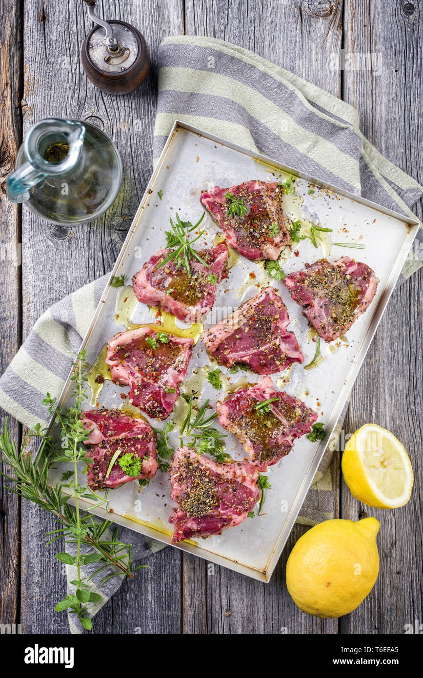 Raw TBone Lamb Steak with Seasonings as top view on a metal sheet