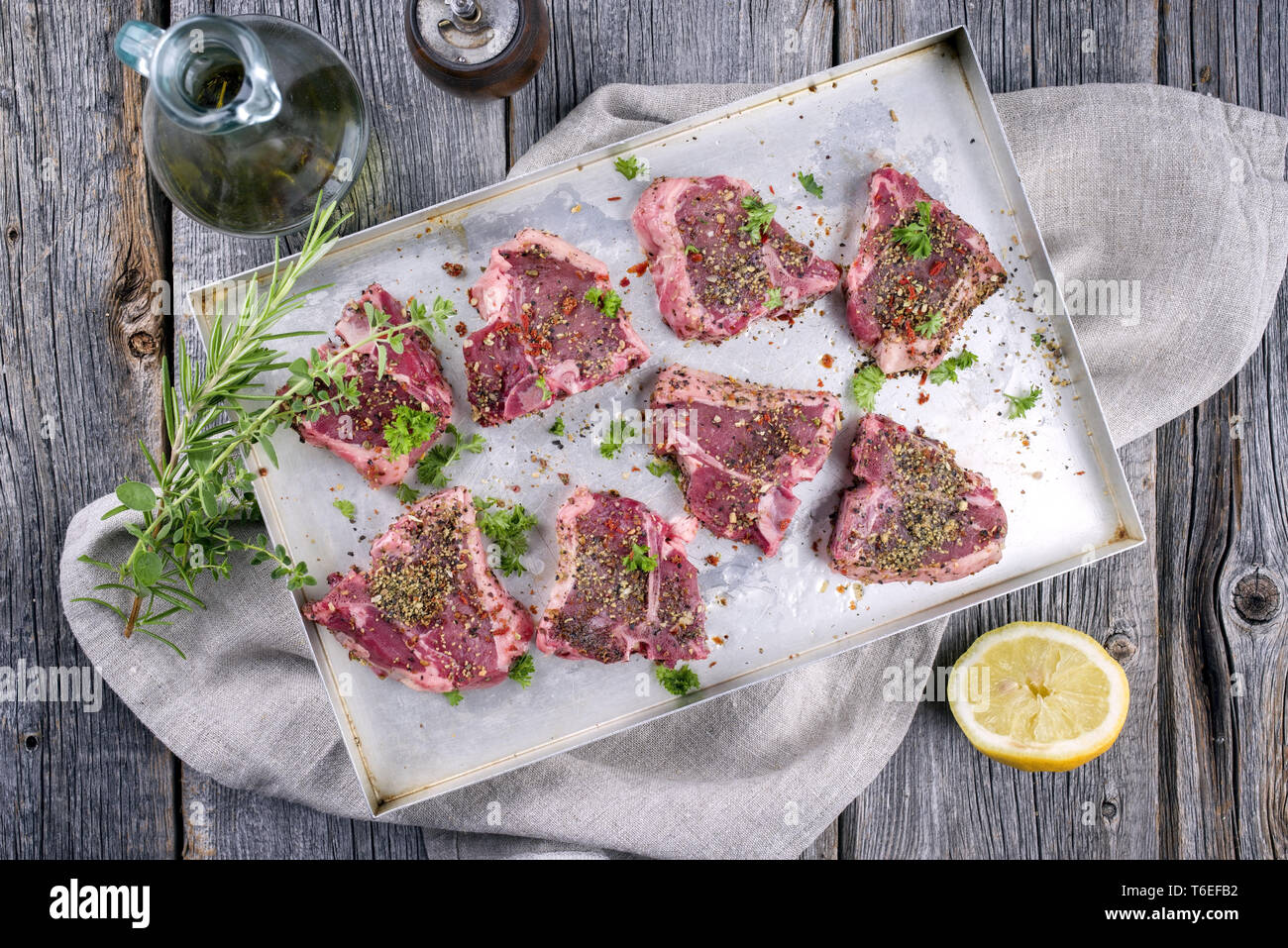 Raw TBone Lamb Steak with Seasonings as top view on a metal sheet
