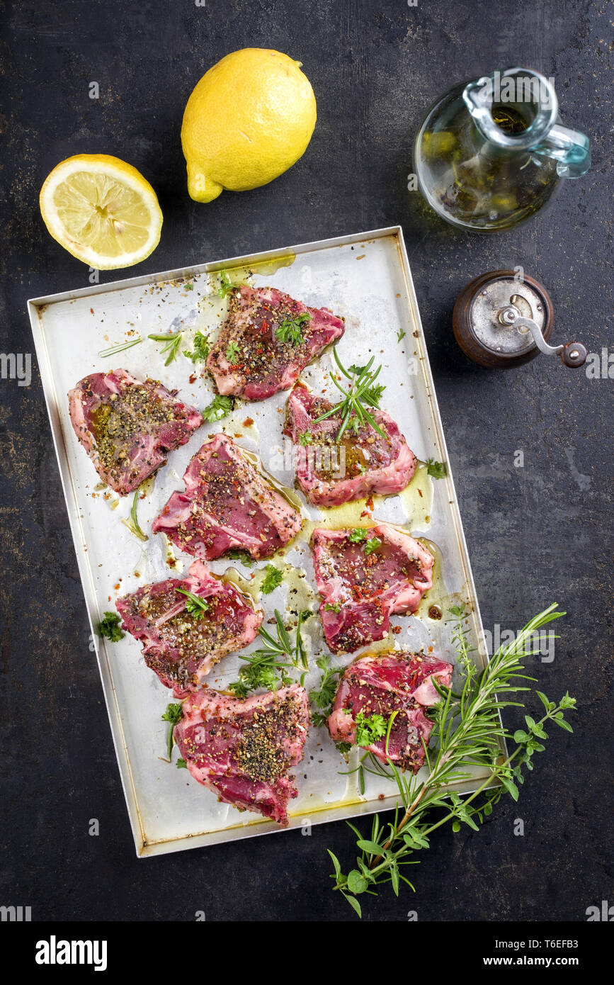 Raw TBone Lamb Steak with Seasonings as top view on a metal sheet