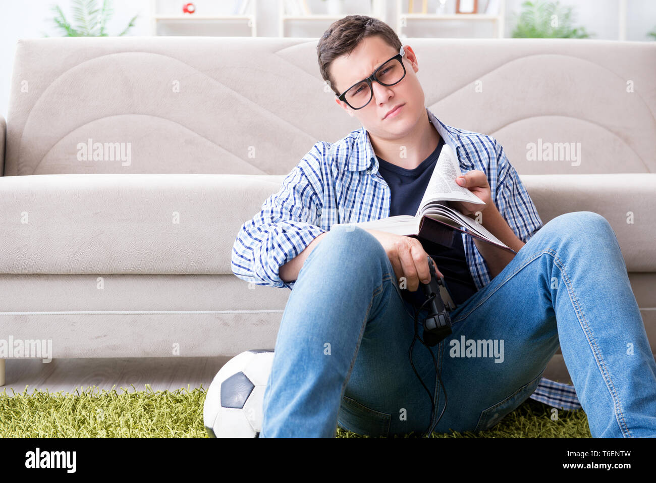 Young student trying to balance studying and playing games Stock Photo ...