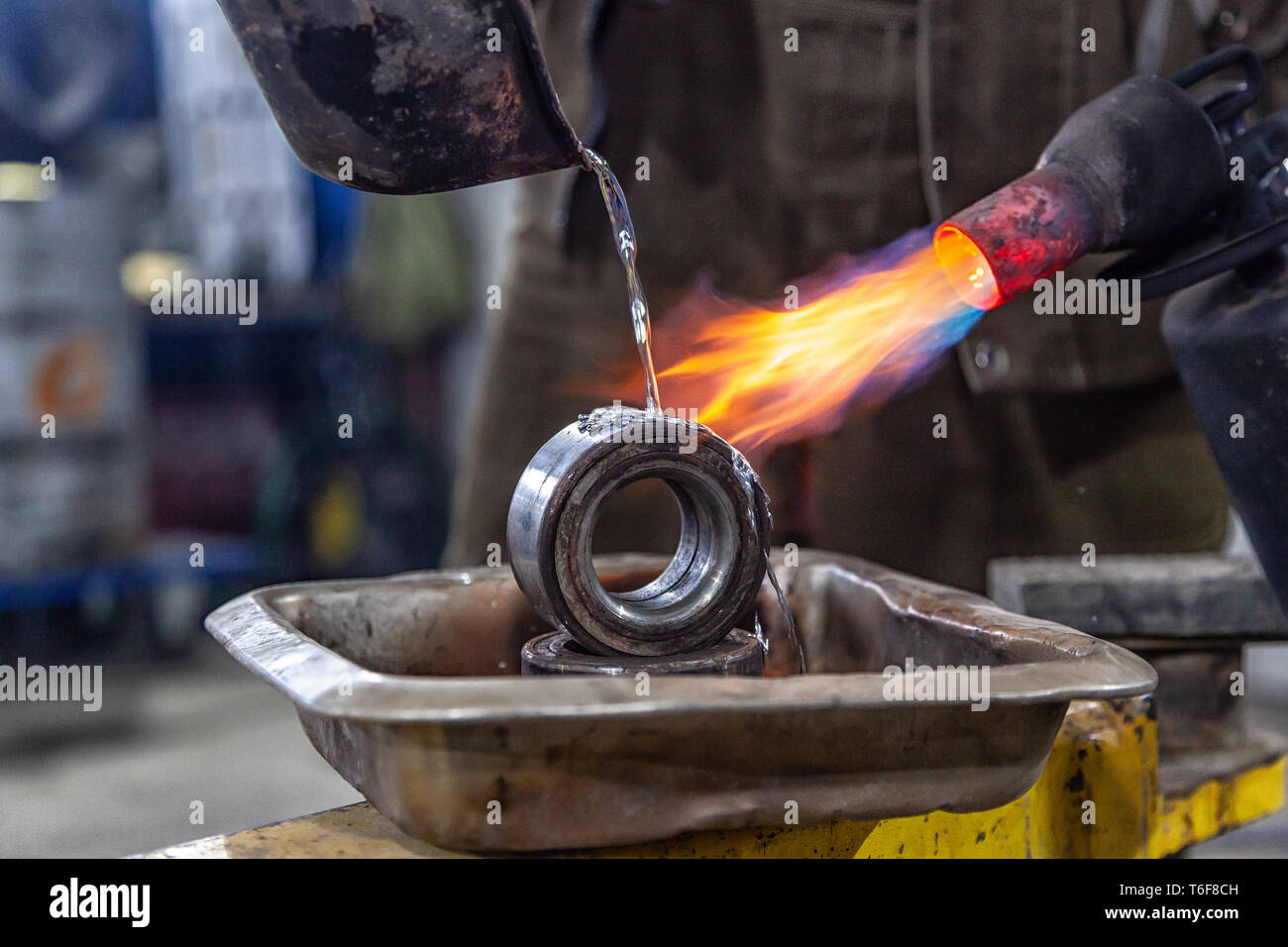 Professional male worker using a gas torch to melt lead metal. Closeup
