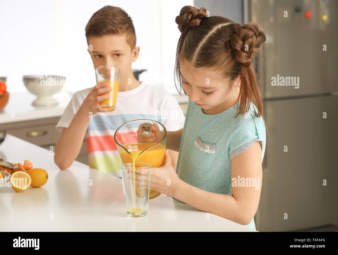 Funny little girl pouring citrus juice into glass at home Stock Photo