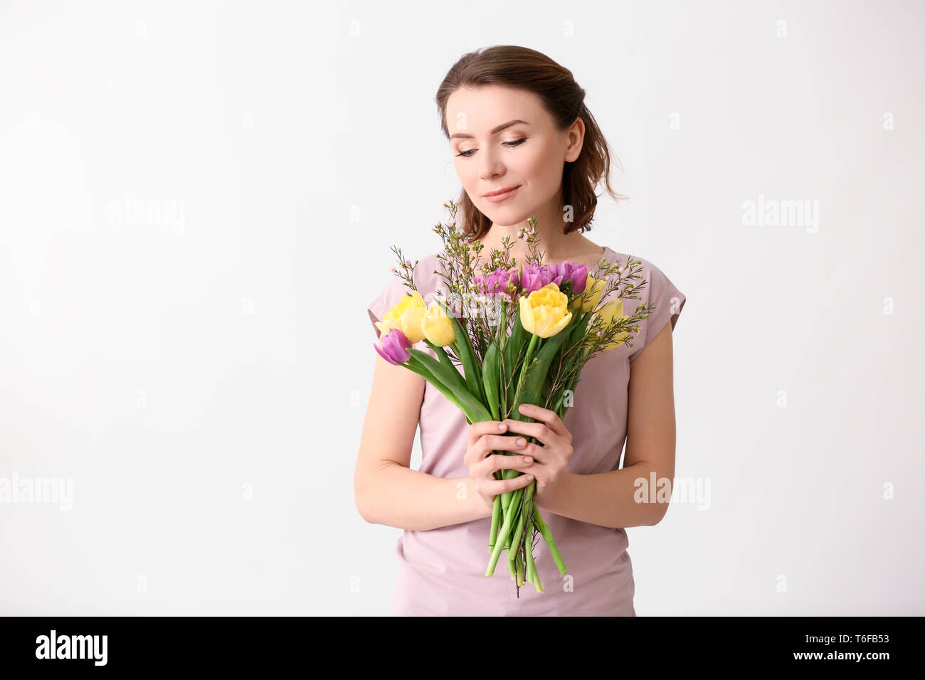 Beautiful woman with bouquet of flowers on light background Stock Photo ...