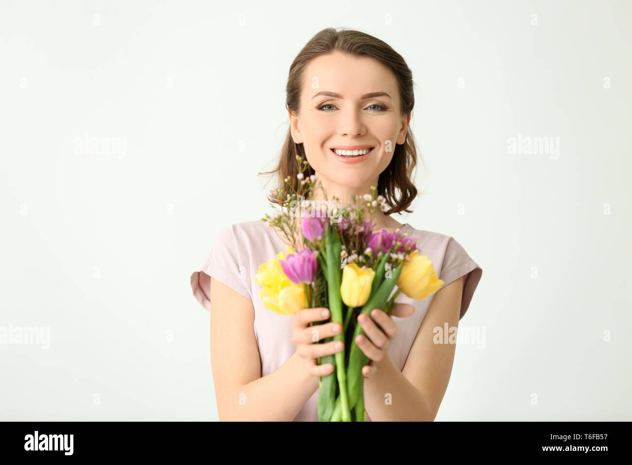Beautiful woman with bouquet of flowers on light background Stock Photo ...
