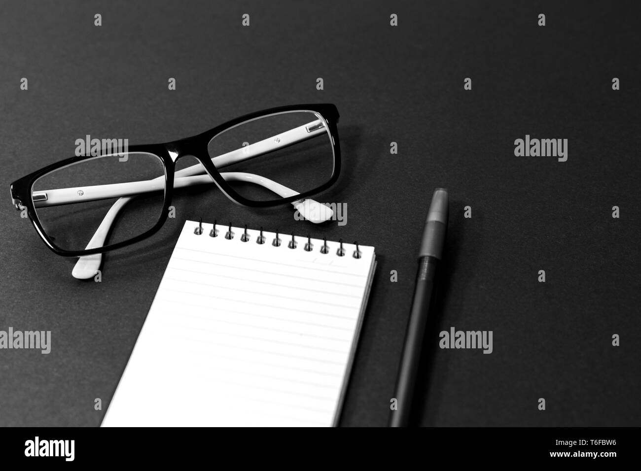 Generic glasses, notepad and pen in a black and white theme flat lay, business, modern, minimal concept Stock Photo