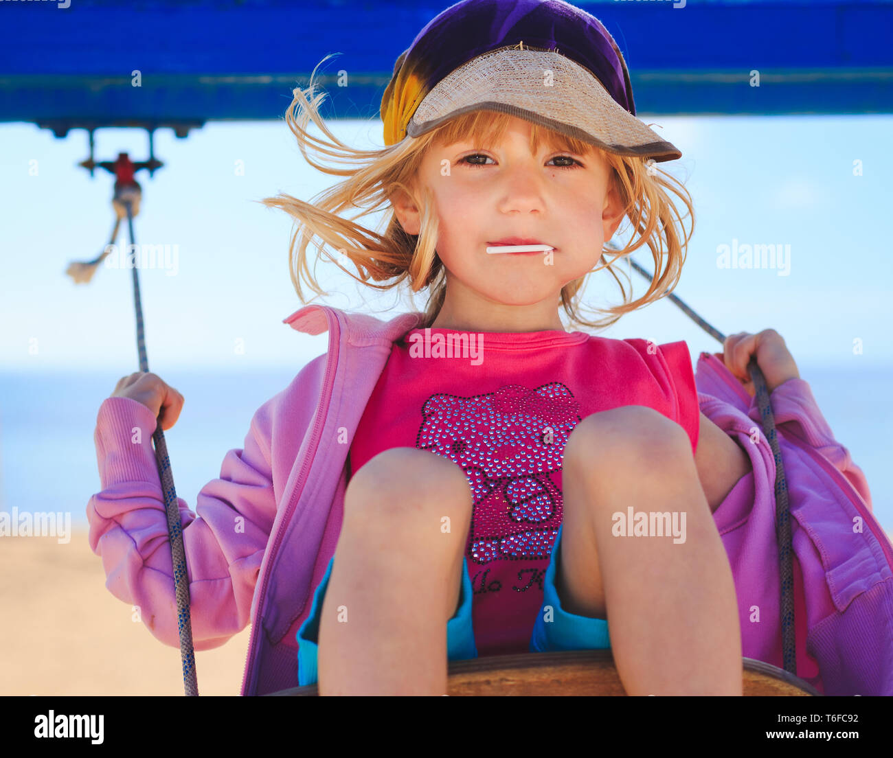 Young girl on a swing with seascape in the background Stock Photo