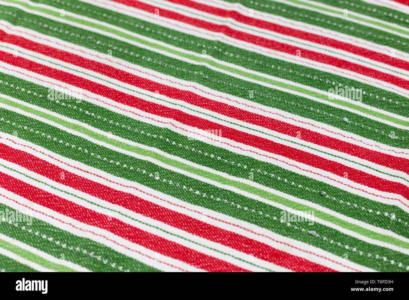 Red, white & green striped Christmas cloth laying flat for background