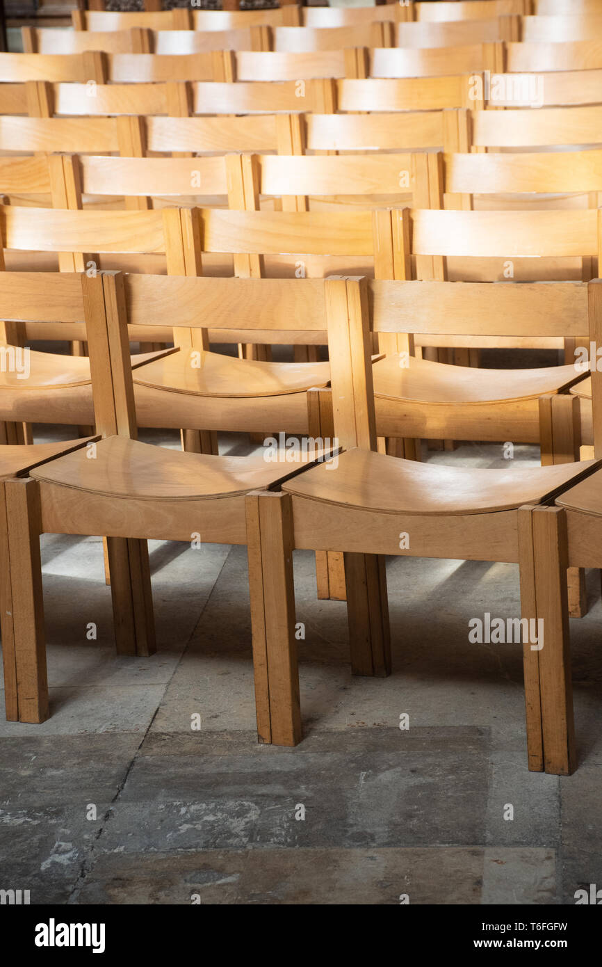 Plain wooden chairs in rows inside Church Stock Photo