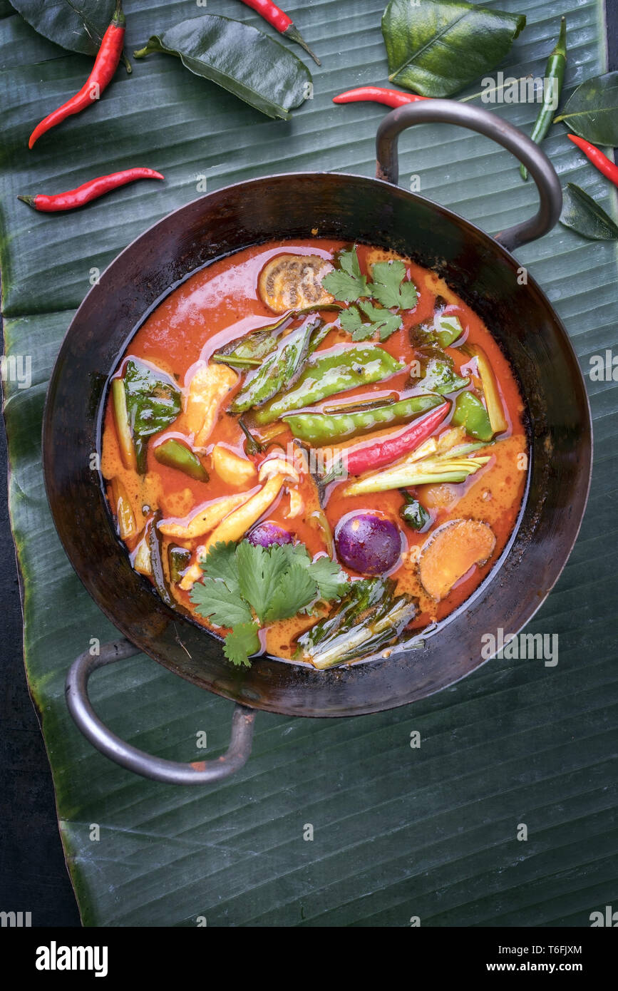 Traditional Thai kaeng phet red curry with vegetables as top view in a wok on a banana leaf Stock Photo