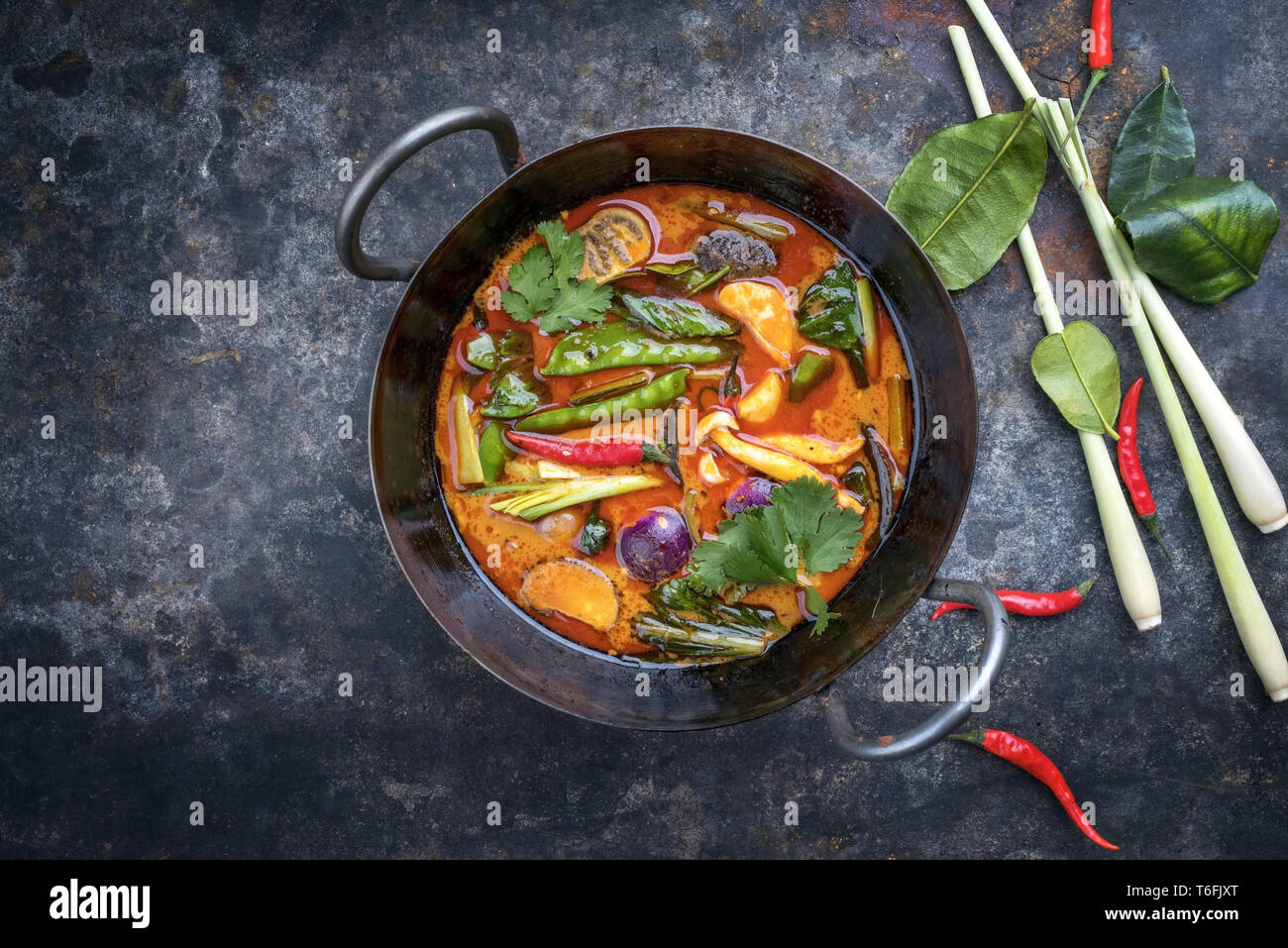 Traditional Thai kaeng phet red curry with vegetables as top view in a wok with copy space left Stock Photo
