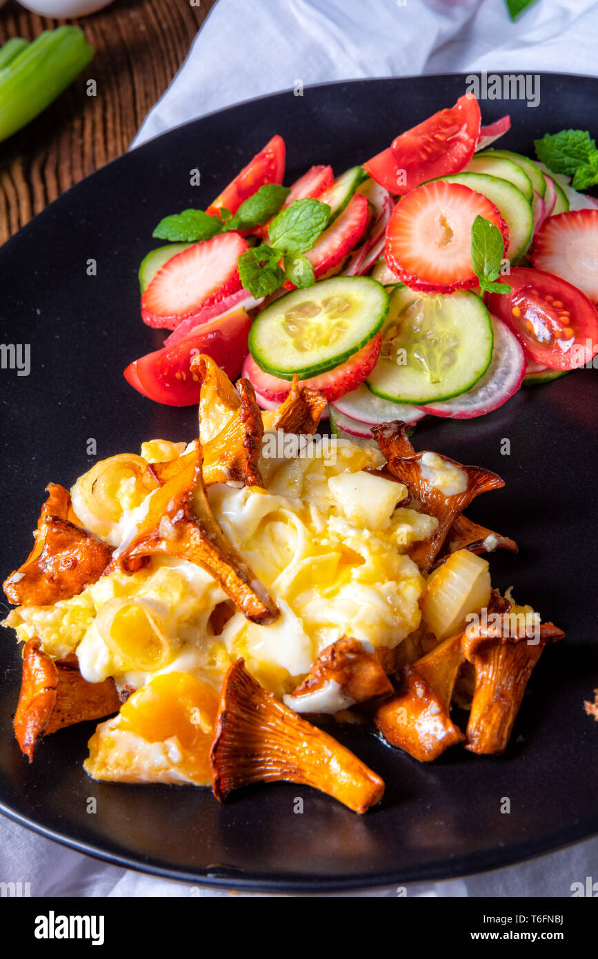 fresh chanterelles with scrambled eggs and a green salad Stock Photo