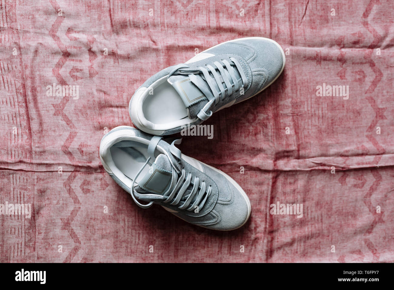 A pair of fashionable blue suede sneakers on a white sole with white accents on a pink background Stock Photo