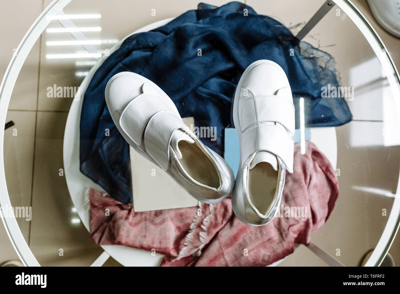 fashionable white sneakers with a star made of rhinestones on the heel on a glass table Stock Photo