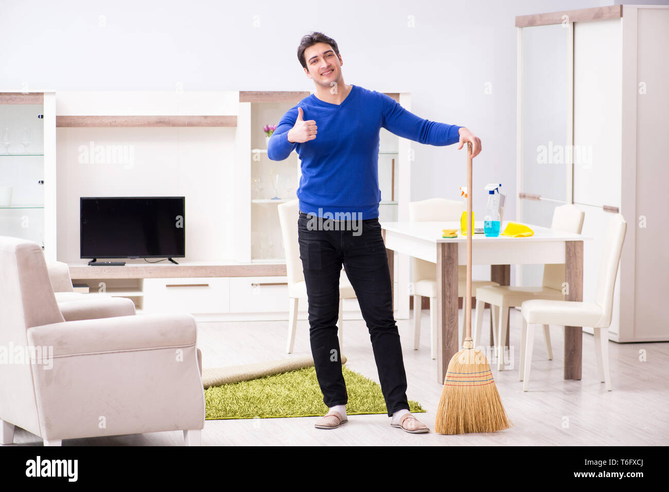 Young man cleaning floor with broom Stock Photo Alamy