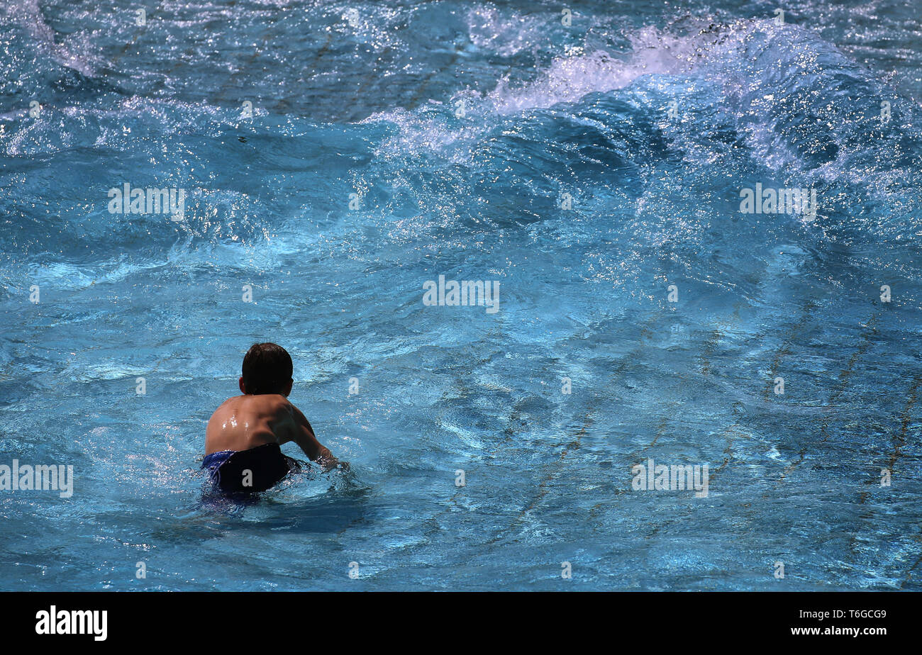 01 May 2019, Bavaria, Landsberg am Lech: A young visitor to the open-air swimming pool enjoys the floods of the wave pool in the Landsberg Inselbad. The bath traditionally opens the bathing season on 1 May. Photo: Karl-Josef Hildenbrand/dpa Stock Photo