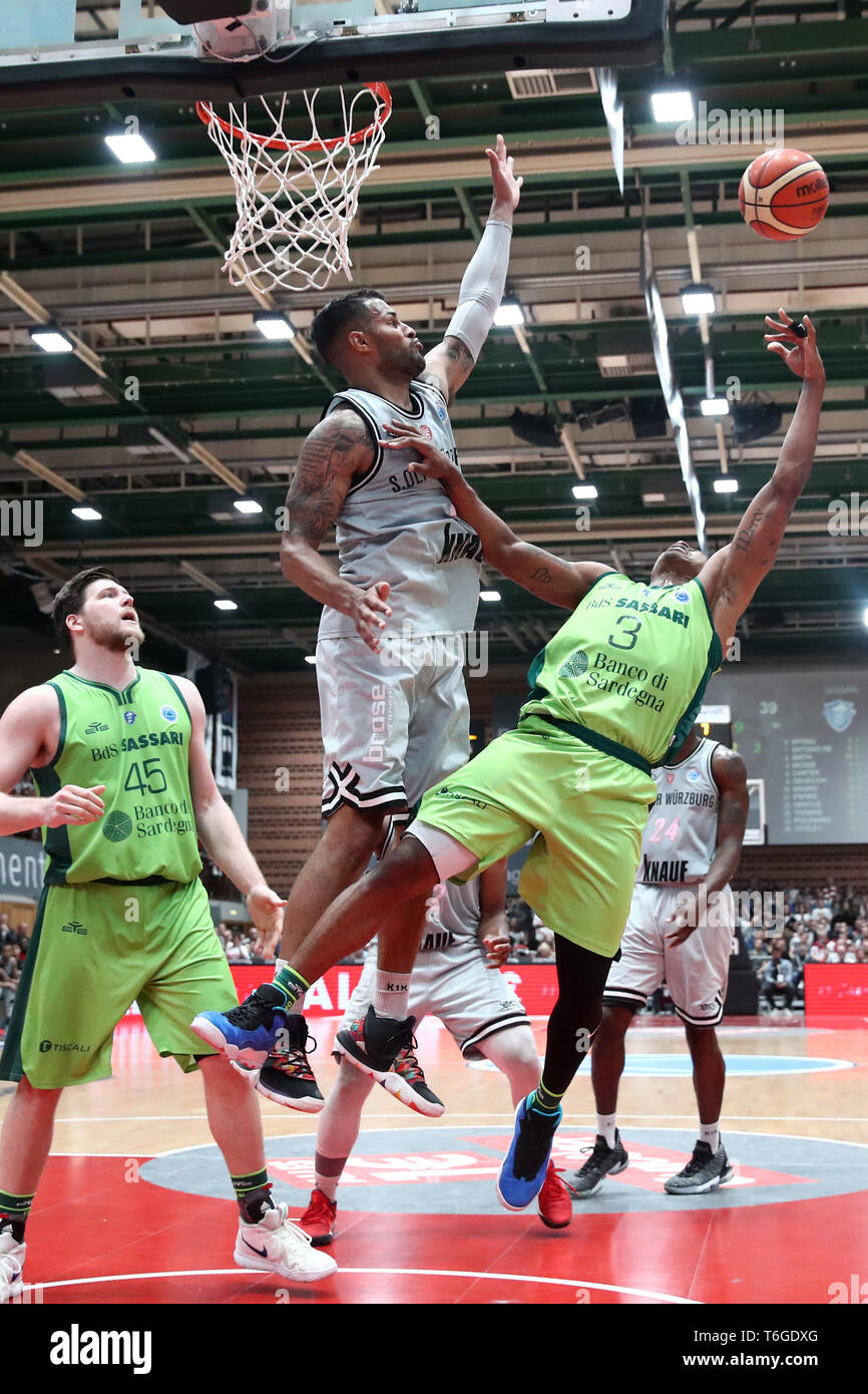 01 May 2019, Bavaria, Würzburg: Basketball: Europe Cup, s.Oliver Würzburg - Dinamo  Sassari, knockout round, finals, second legs, in the s.Oliver Arena. Devin  Oliver (M) from Würzburg blocks Tyrus McGee (r) from