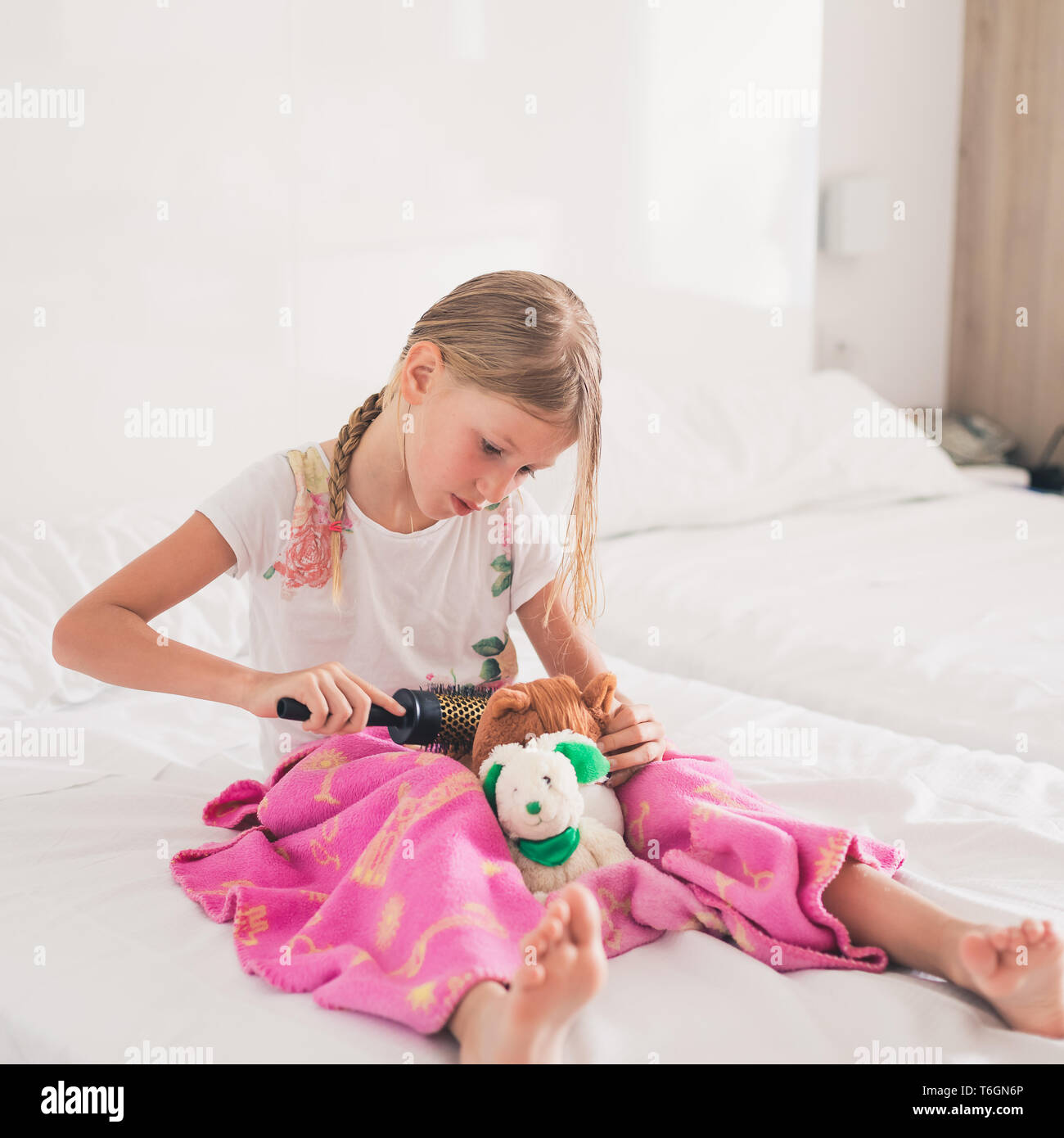 Young girl combing hair of cuddly toy Stock Photo