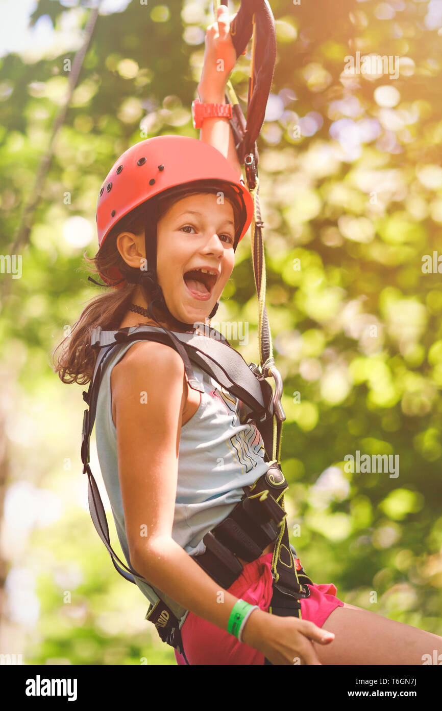 Young girl going by flying fox in forest rope park Stock Photo