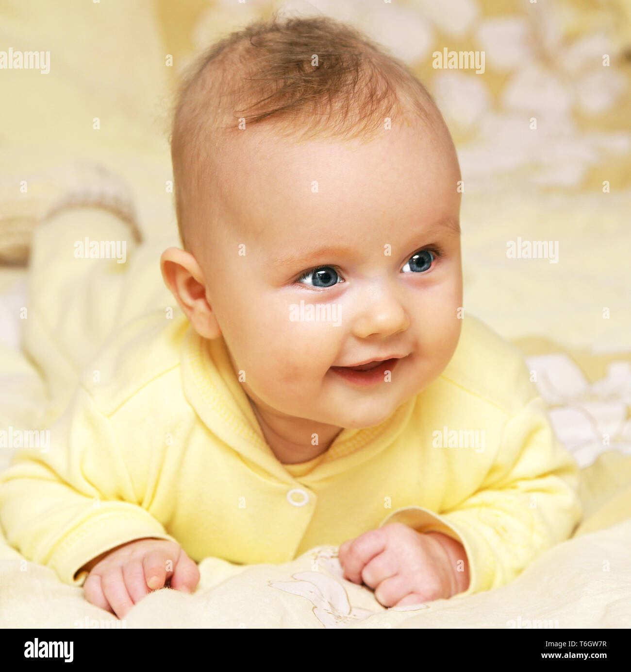 newborn european baby girl boy smiling head up 3 months old in yellow