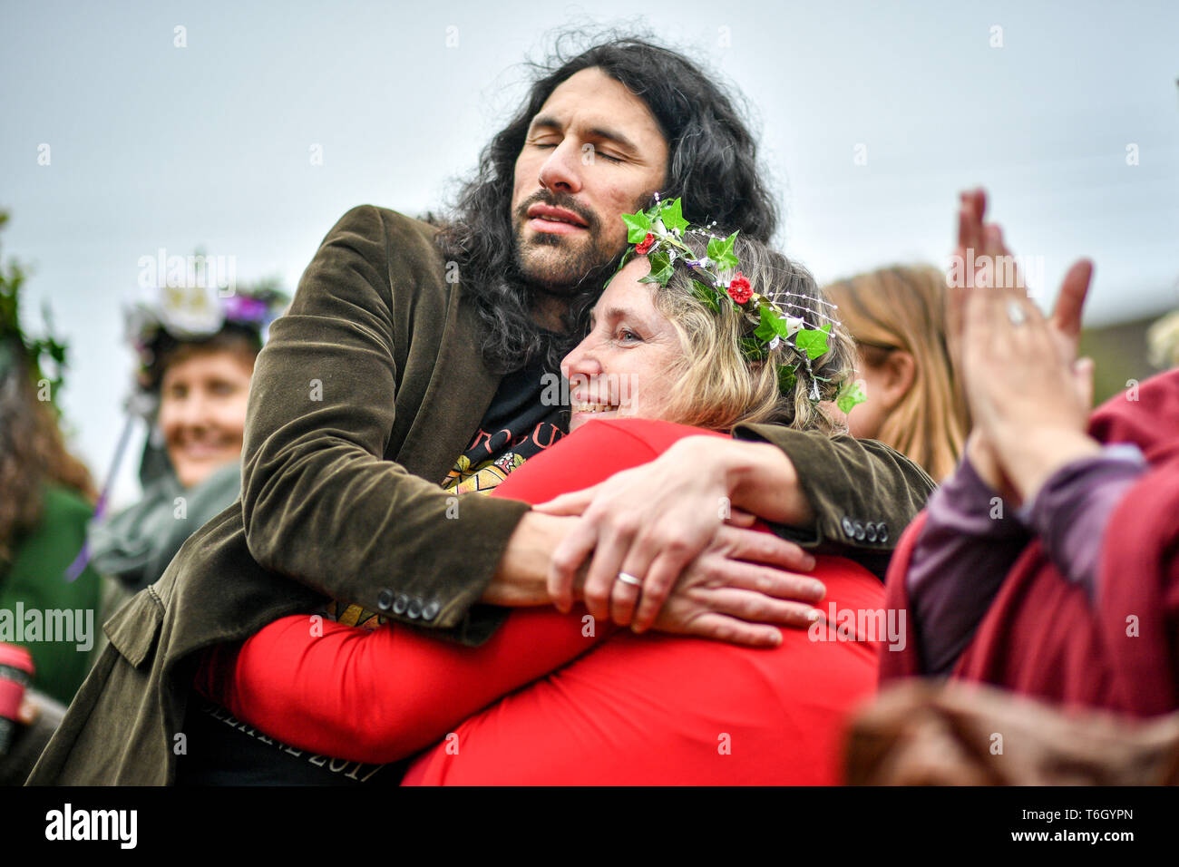 People hug during the Beltane celebrations at Glastonbury Chalice Well, where people gather to observe a modern interpretation of the ancient Celtic pagan fertility rite of Spring. Stock Photo