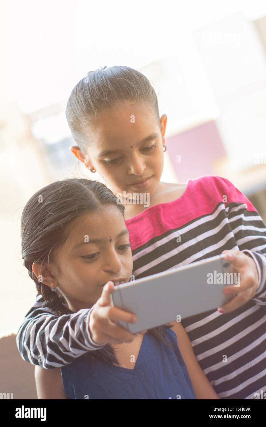 Two Indian kids watching mobile device at outdoor. Stock Photo