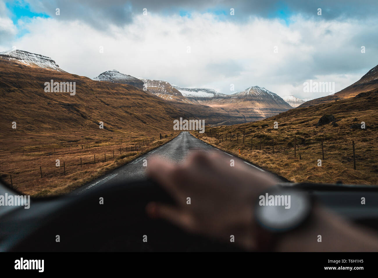 Driver's perspective from the inside of a car during a road trip through snow-covered valleys on the Faroe Islands with scenic views (Faroe Islands) Stock Photo