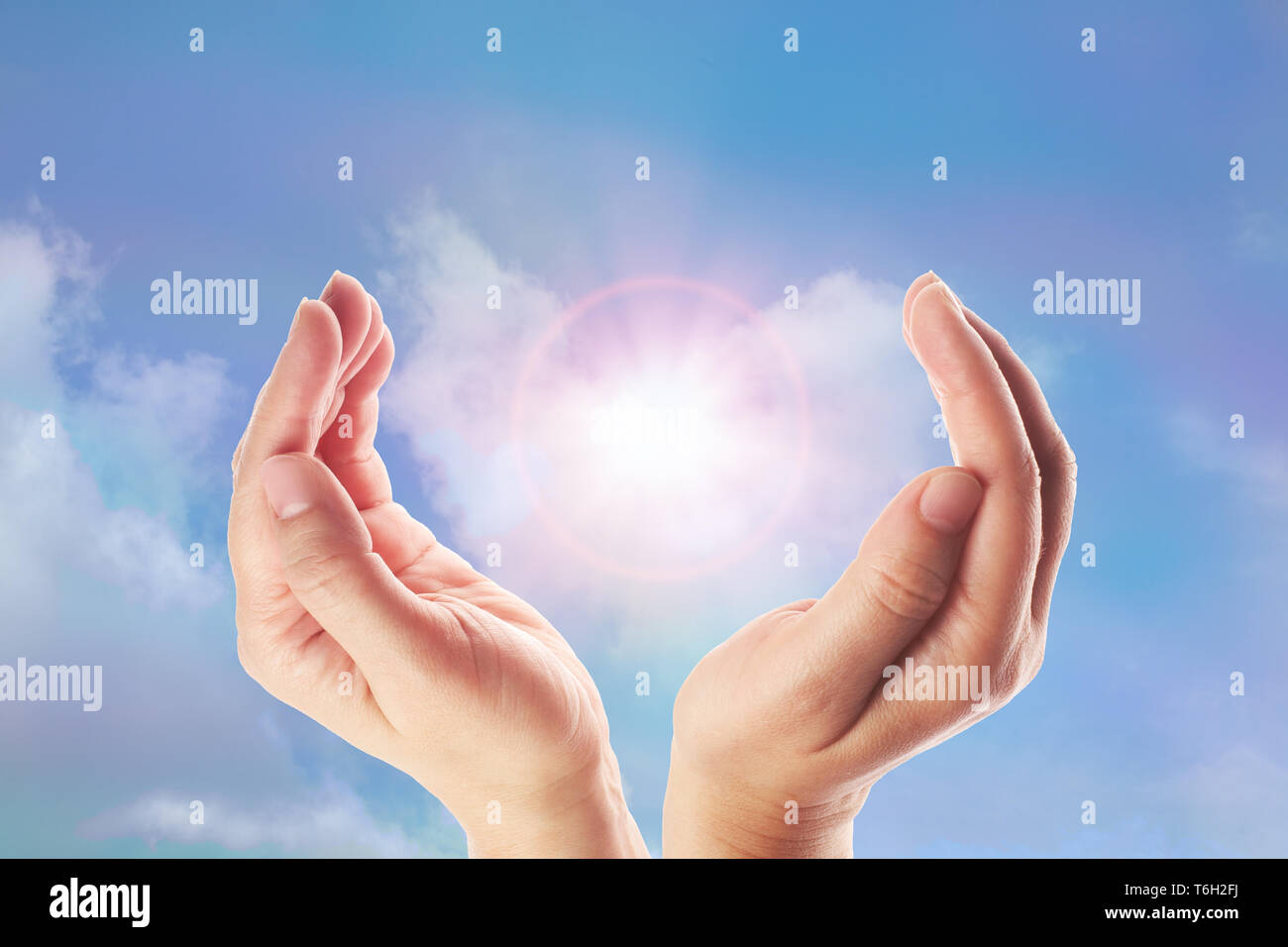 Healing hands with bright sunburst on rainbow background Stock Photo