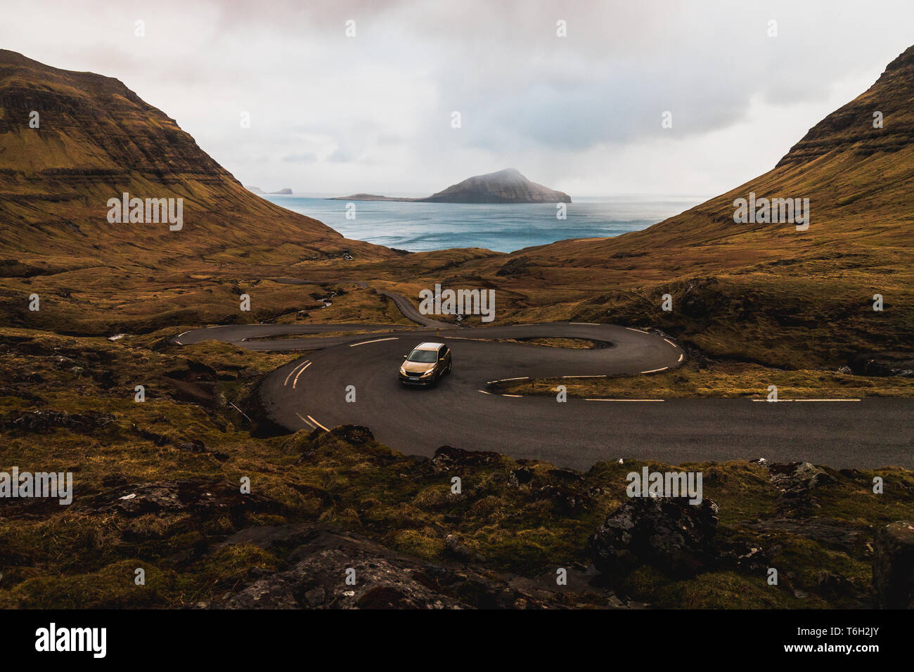 Car driving up serpentines on the island Streymoy near the village Norðradalur with view of Koltur island (Faroe Islands, Denmark, Europe) Stock Photo