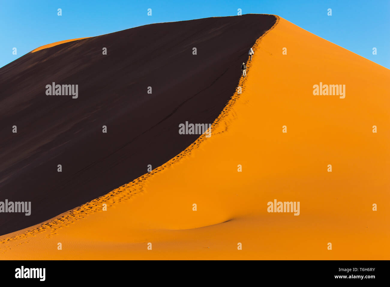 Tourists climb to the top of the dune Stock Photo