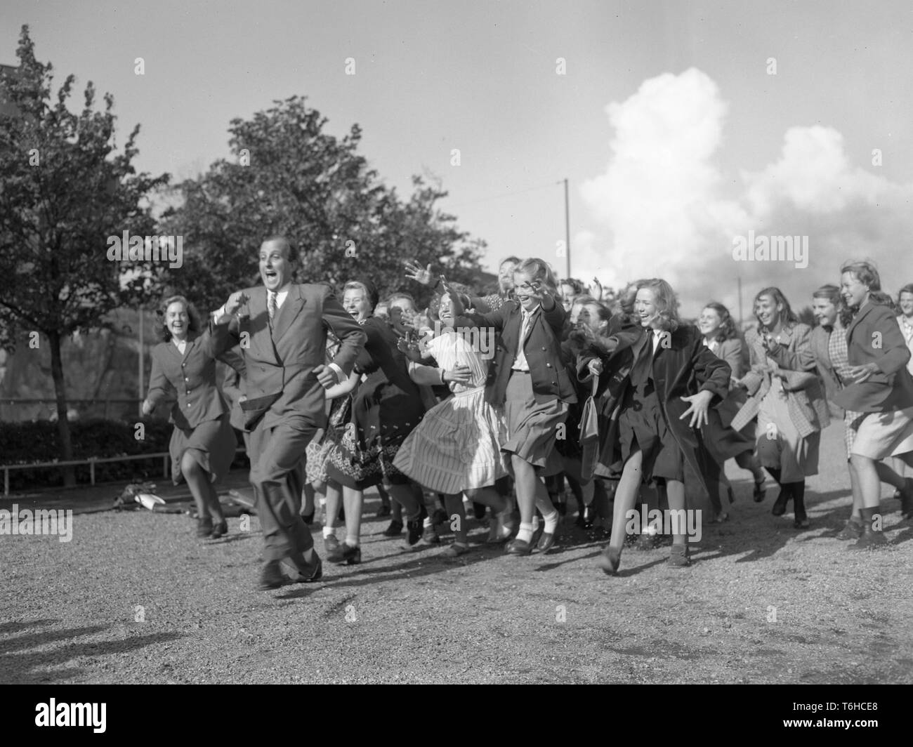 1940s man. A man is being chased by women running after him with their arms out like they would like to catch him.  Photo Kristoffersson ref 223A-11. Sweden 1948 Stock Photo