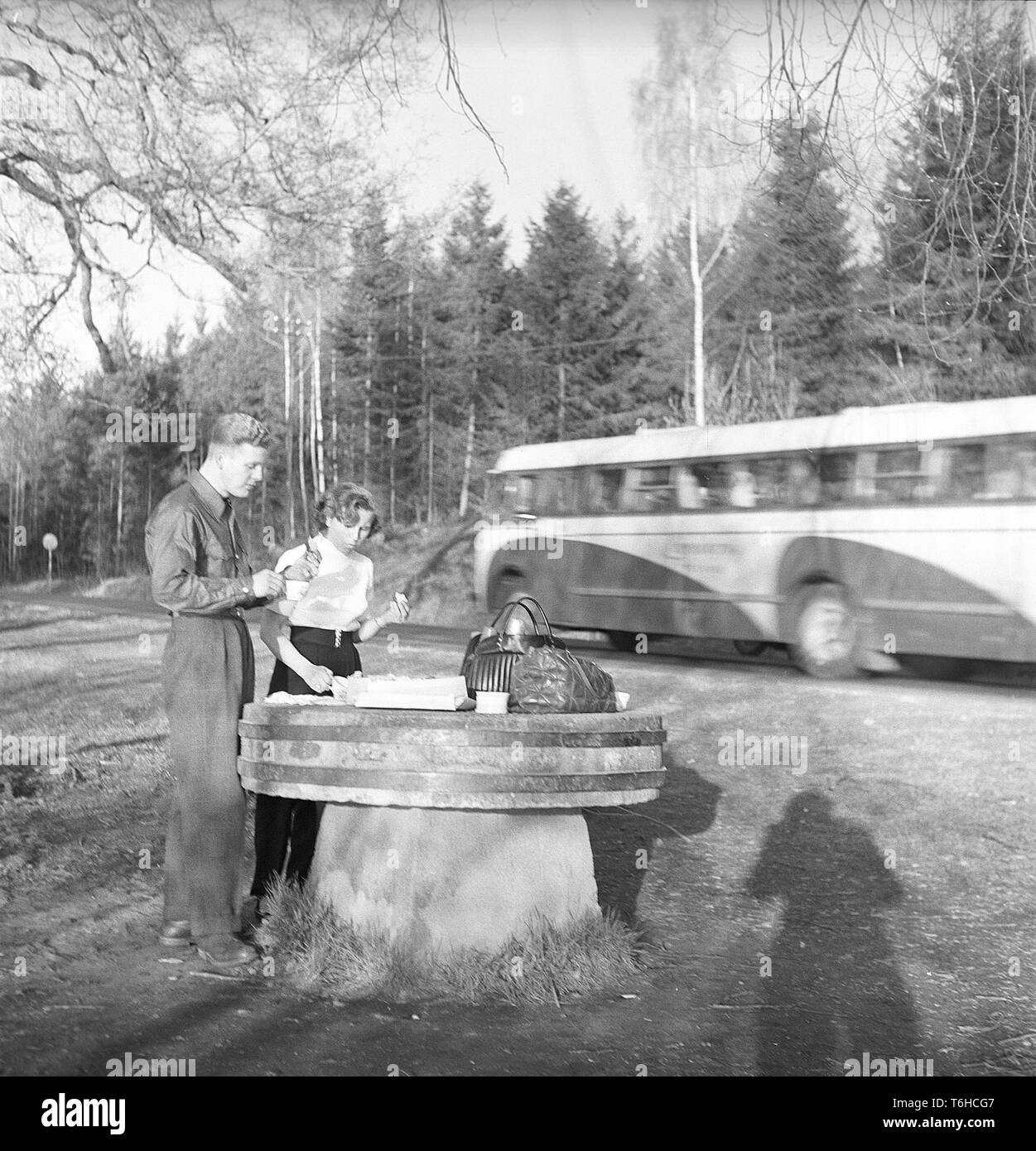 Lifestyle in the 1950s. A young couple has stopped to have a coffee and a fika time and a sandwich by the roadside. An old millstone makes a good table for the picnic. Photo Kristoffersson Ref BF76-7. Sweden 1952 Stock Photo