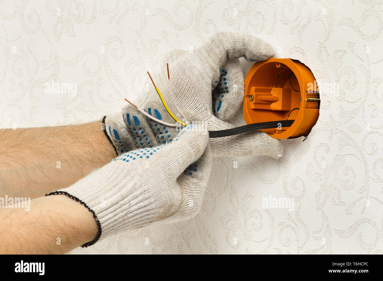hands of an worker fastens the socket box on the wall Stock Photo