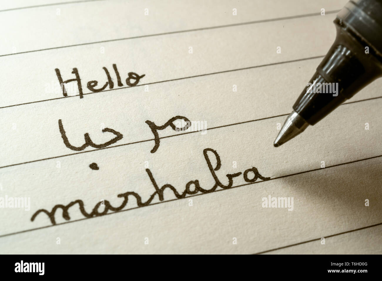 Beginner Arabic language learner writing Hello word Marhaba in abjad Arabic alphabet on a notebook close-up shot Stock Photo