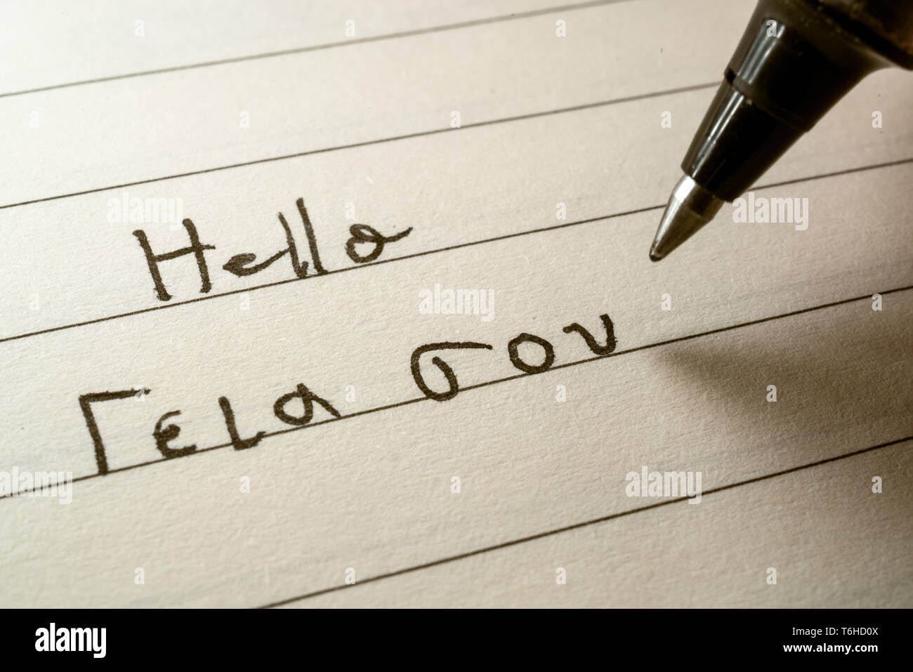 Beginner Greek language learner writing Hello word in greek alphabet on a notebook close-up shot Stock Photo