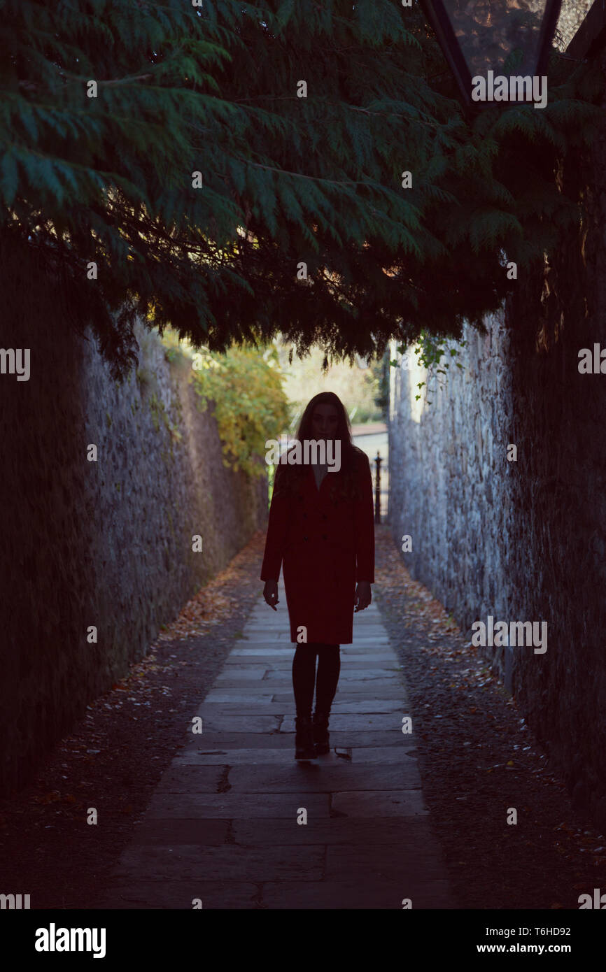 Woman walking down a narrow dark alley all on her own Stock Photo