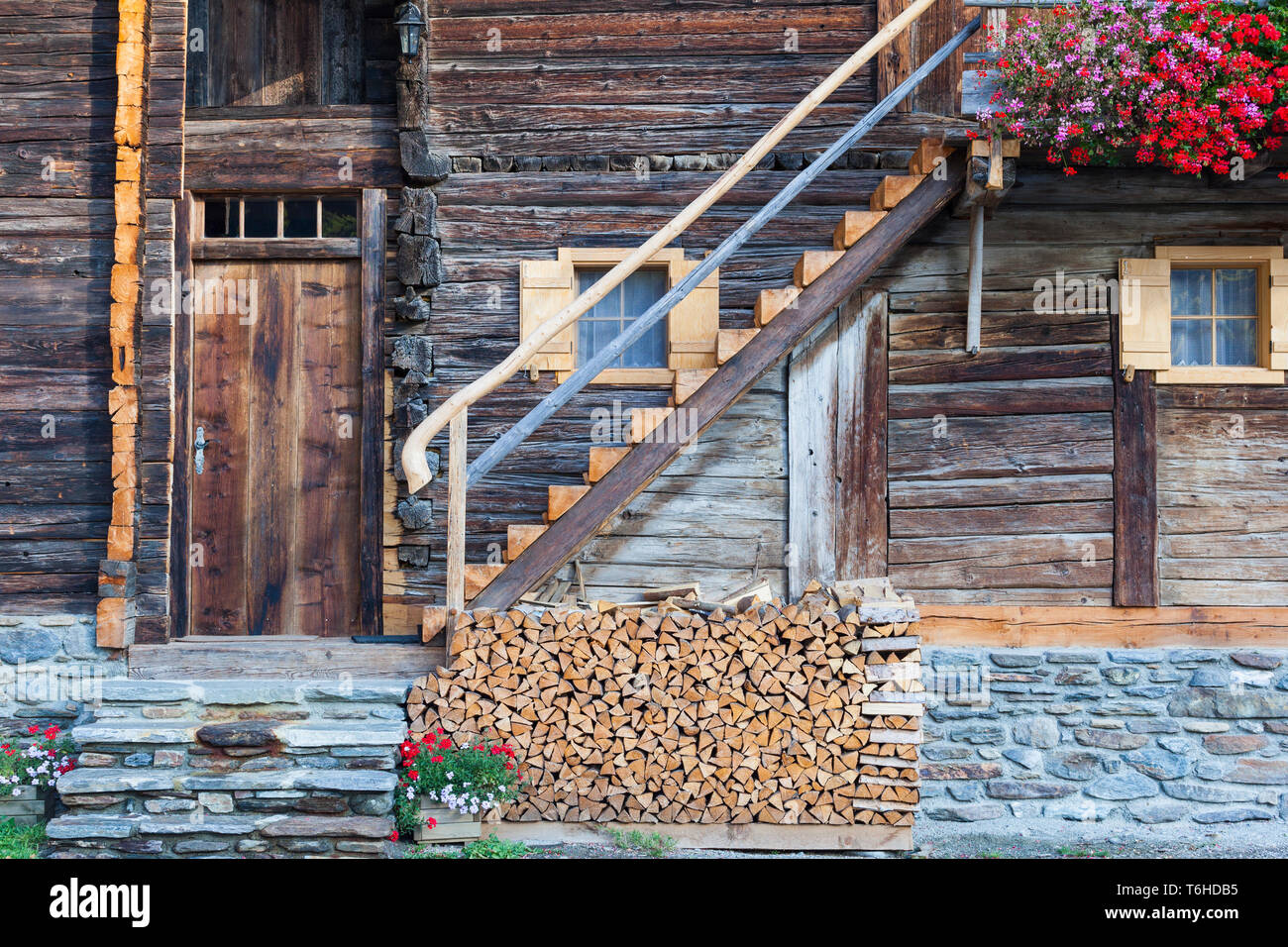 Old Alphus with flowers and a firewood pile Stock Photo
