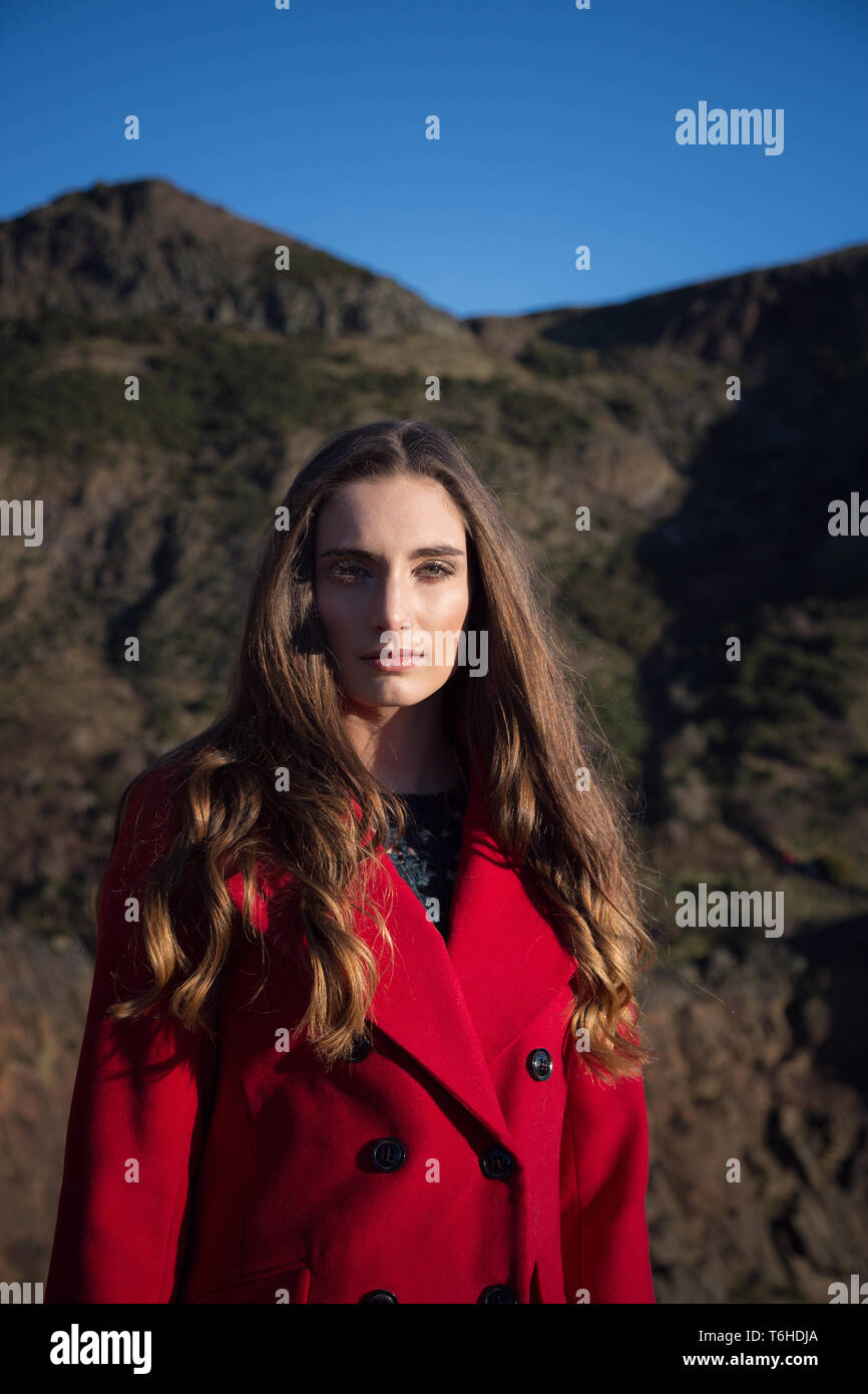 Woman in red coat looking very serious, clearly troubled and alone Stock Photo