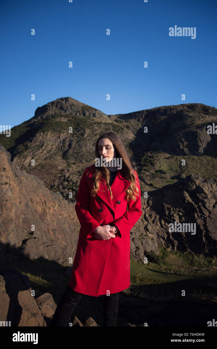 Woman in red coat looking very serious, clearly troubled and alone Stock Photo