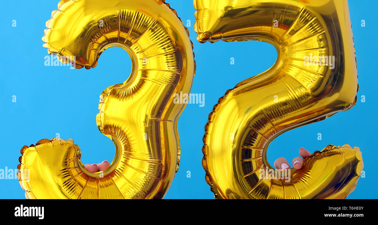 Gold foil number 35 celebration balloon on a blue Stock Photo