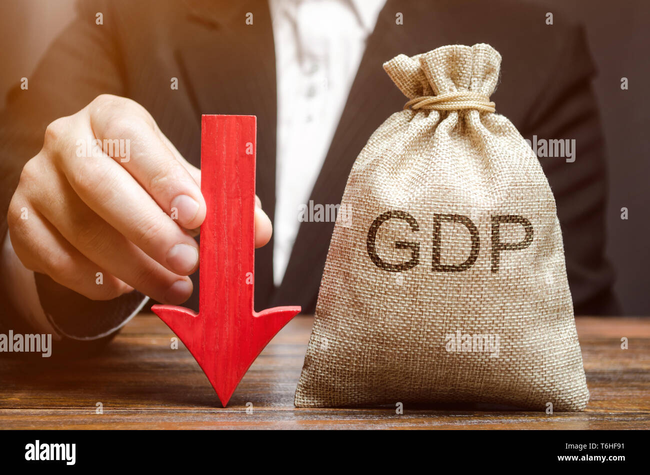 A bag with the word GDP and a down arrow in the hands of a businessman. Decline and decrease of GDP - failure and breakdown of economy and finances le Stock Photo