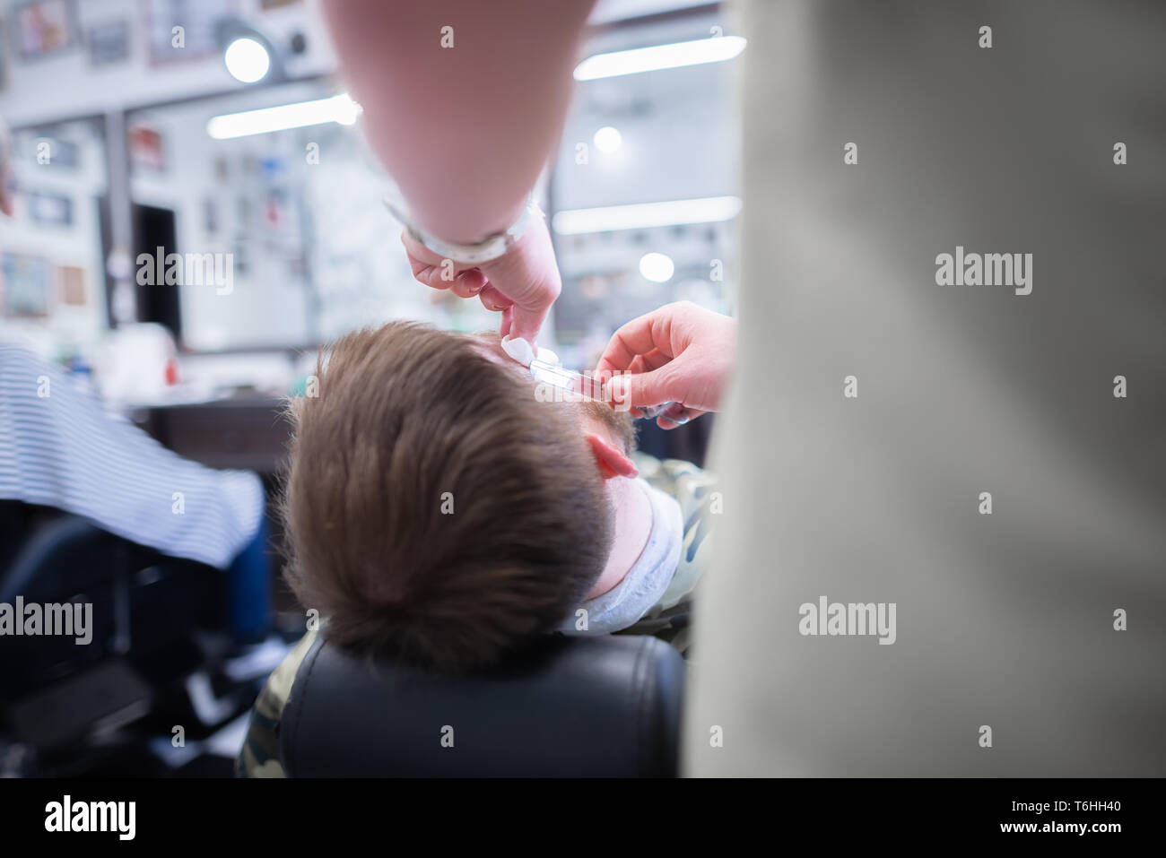 Men's haircut in barbershop. Shave a dangerous razor. Stock Photo
