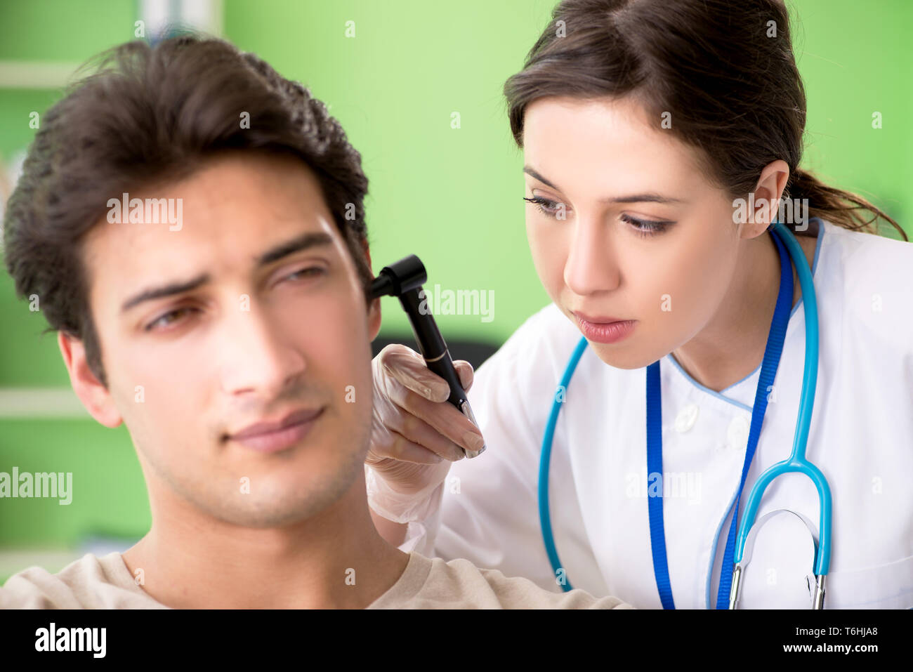Female doctor checking patient's ear during medical examination Stock