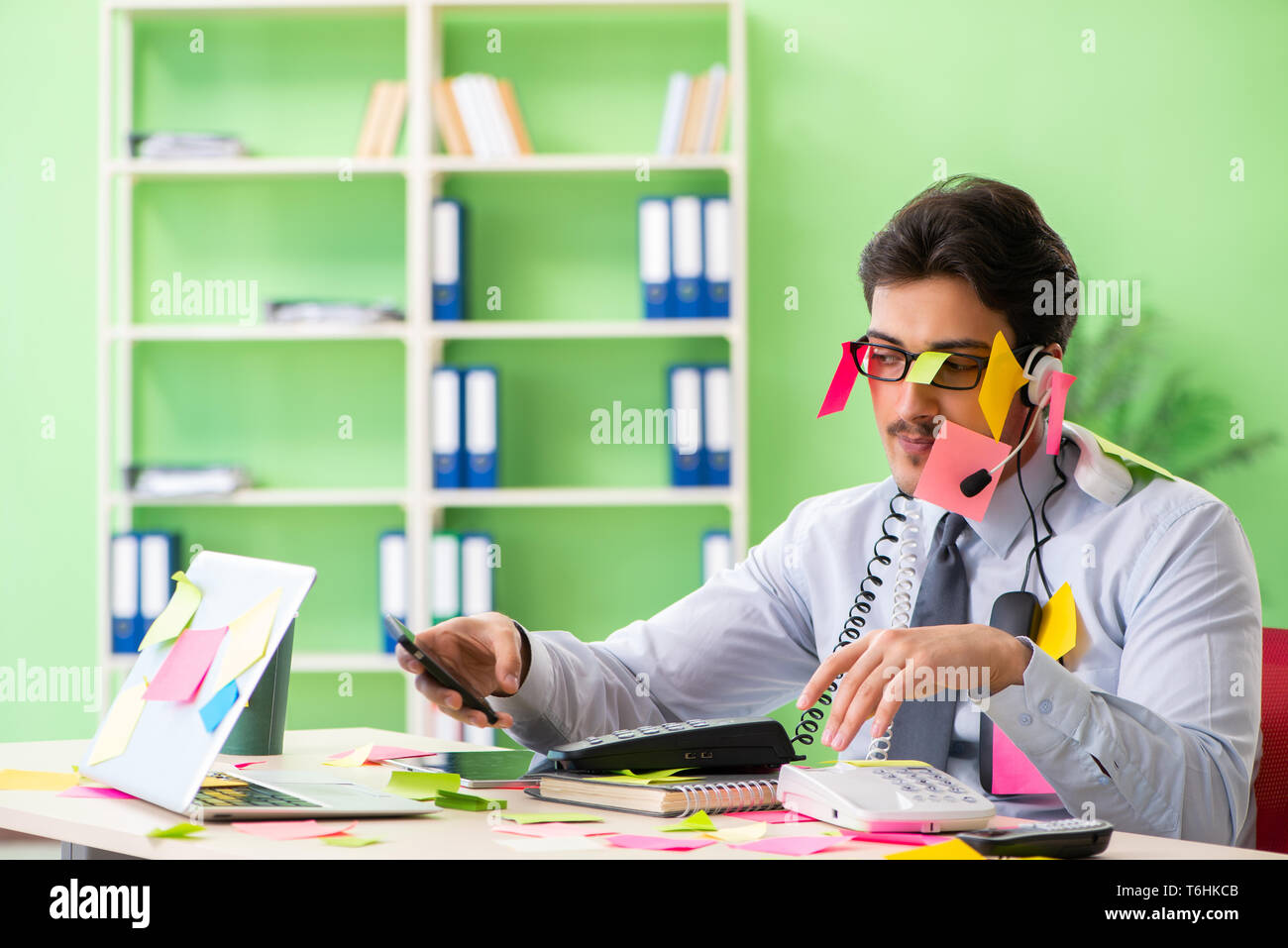 Young help desk operator working in office with many conflicting Stock