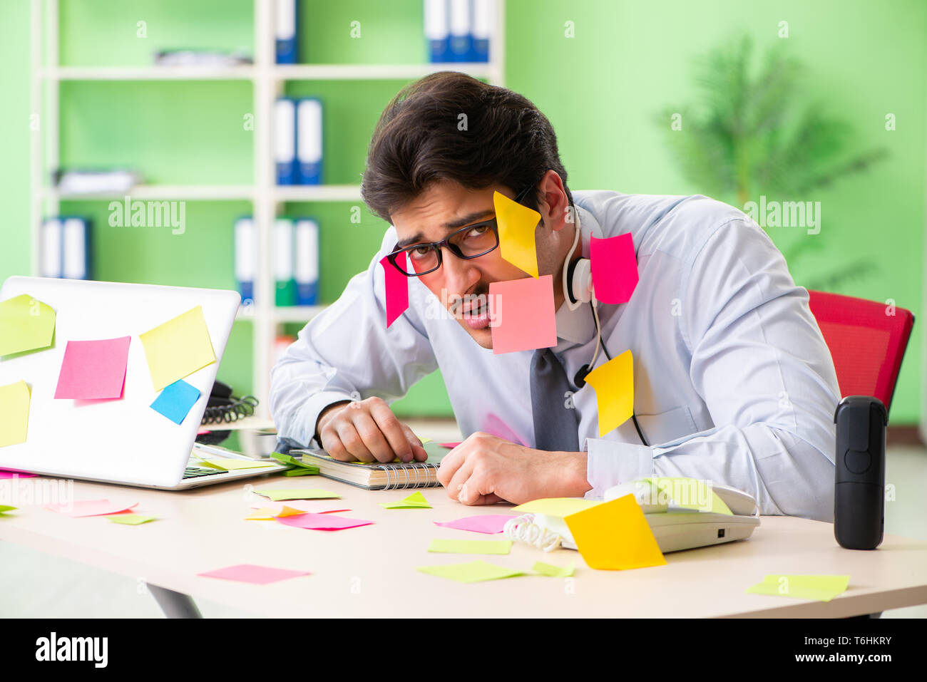 Young help desk operator working in office with many conflicting Stock