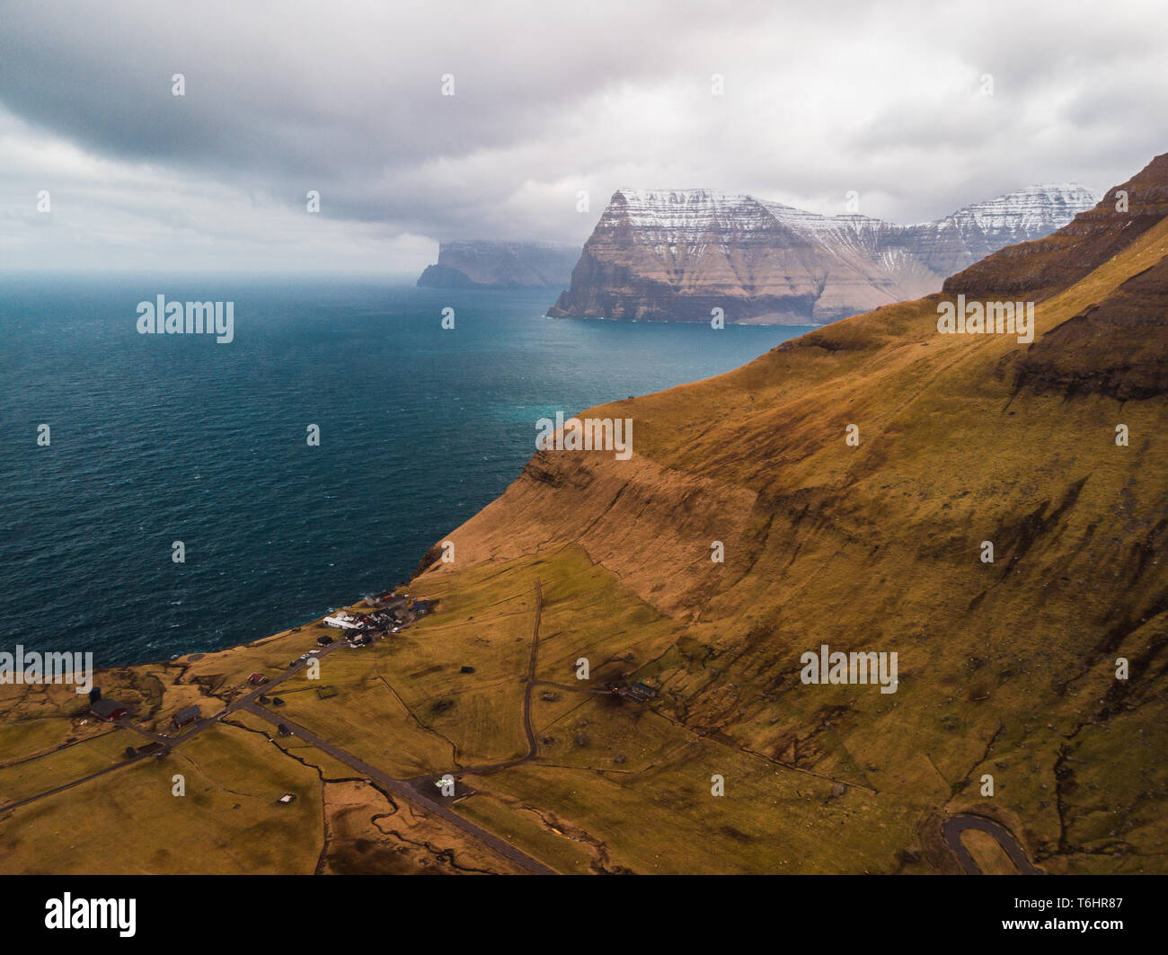 Aerial view of the small village Trøllanes on Kalsoy island with turquoise Atlantic ocean and Kunoy island as background (Faroe Islands, Europe) Stock Photo
