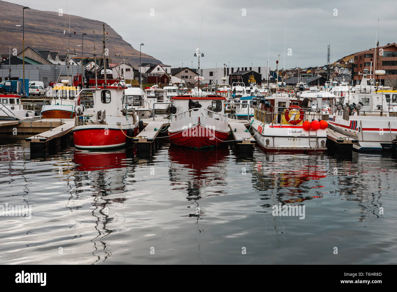 Small fishing and sailing boats in the harbour of Klaksvík during a moody spring morning with calm water (Faroe Islands, Denmark, Europe) Stock Photo
