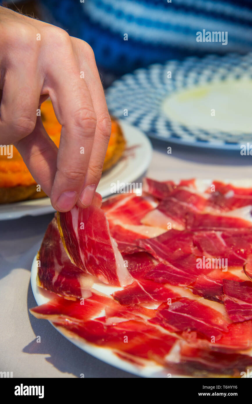 Man's hand having Iberian ham. Spain. Stock Photo