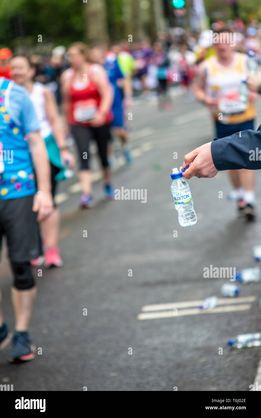 Water station at the London Marathon 2019 serving Buxton water bottles. Plastic bottles. Plastic bottle. Refreshment station for runners. Handing out Stock Photo