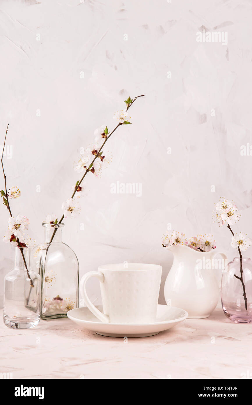 A Stylish White Cup Of Coffee Among Small Vases With Spring